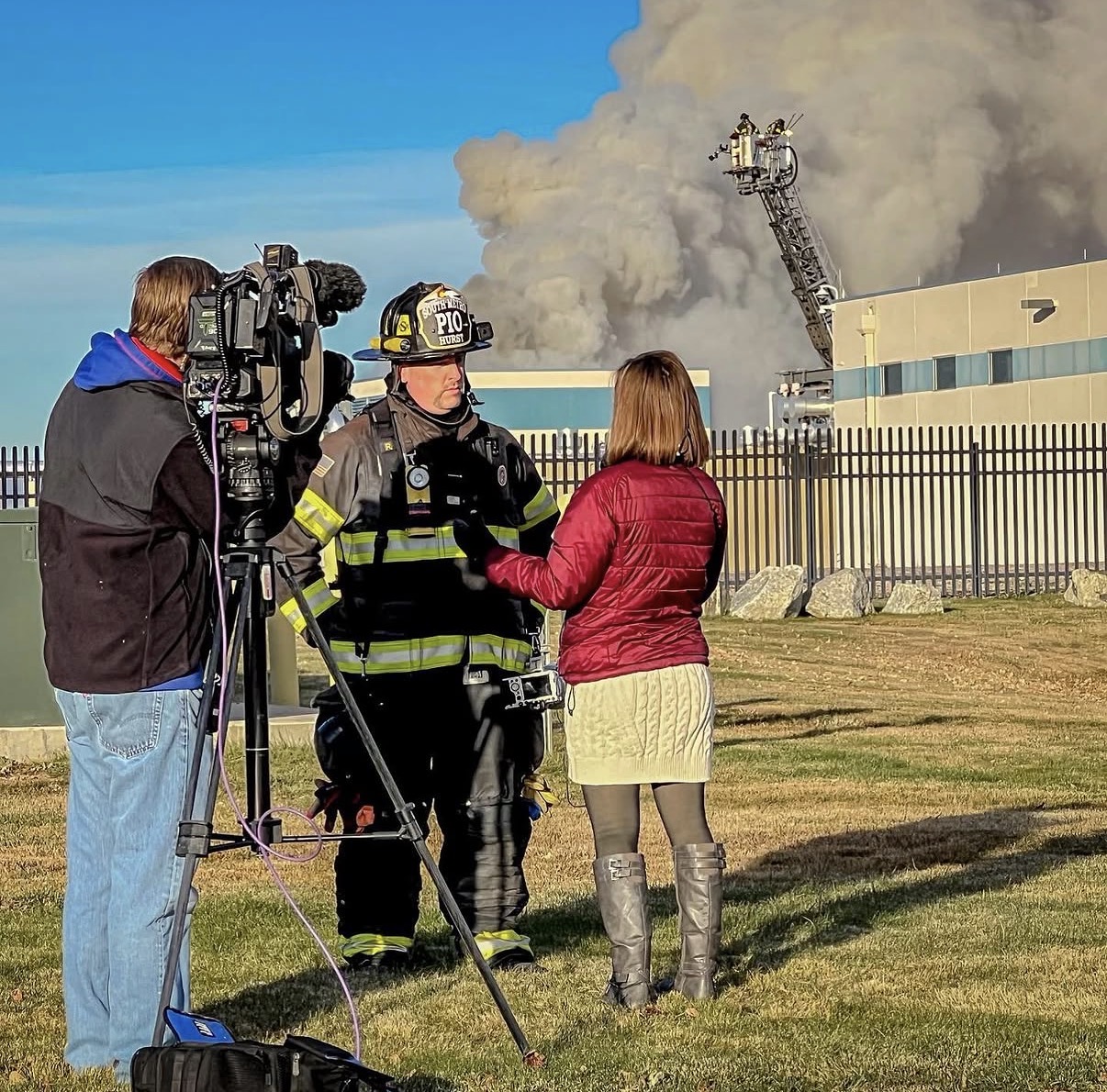 Eric Hurst speaking with a television reporter near an active fire scene